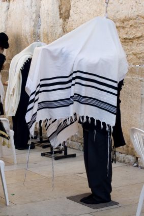 Some tallits (prayer shawls) are large enough to be draped over the head while praying.  In the photo above, the tzitzit are visible on the four corners of the garment hanging down.