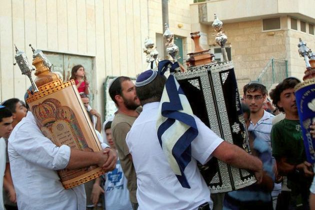 These Torah scrolls are protected by ornately ornamented Sefer Torah tiks (Torah scroll cases).