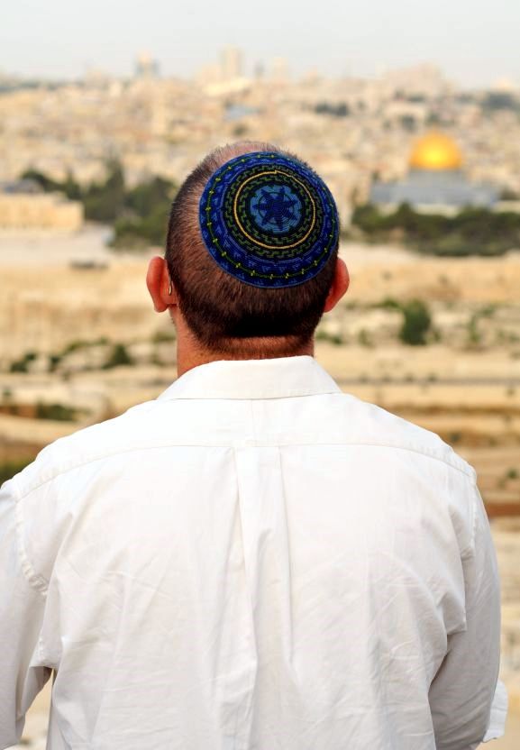 A Jewish man stands on the Mount of Olives facing the Temple Mount in Jerusalem.