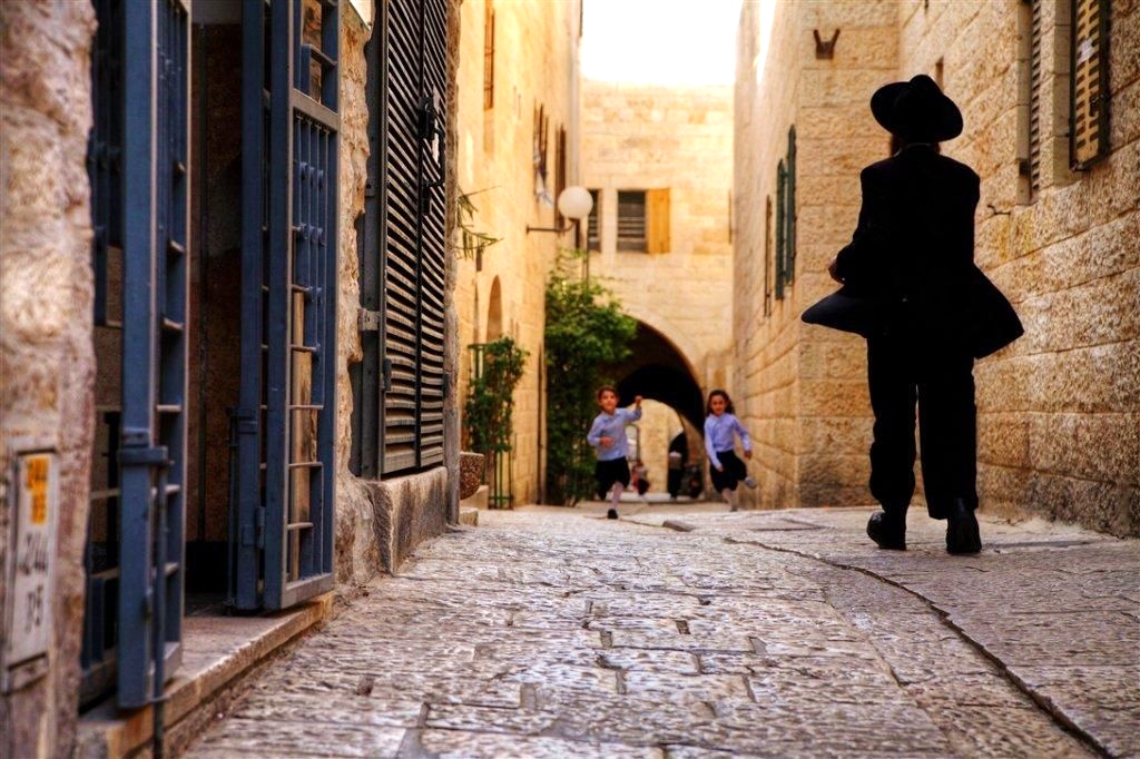 Jewish children run toward their father in a narrow street in Israel. (Photo credit: Go Israel)