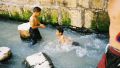 Israeli children, who have exited Hezekiah's Tunnel at the Pool of Siloam, play in the water that originates at the Gihon Spring.