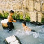 Israeli children, who have exited Hezekiah's Tunnel at the Pool of Siloam, play in the water that originates at the Gihon Spring.