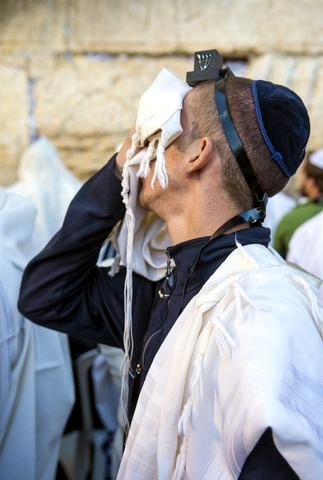 A Jewish man wearing tefillin (phylacteries) recites selichot (prayer for forgiveness and mercy) at the Western (Wailing) Wall during the Days of Awe.