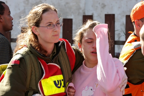 An Israeli soldier helps a civilian during a Hamas bombing of Israel.