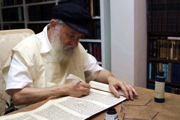 A Jewish scribe handwrites a Torah scroll.