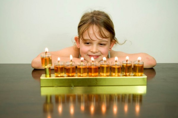 Fully lit oil hanukkiah with the shamash raised at the end.