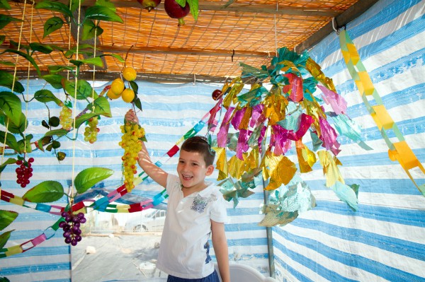 An Israeli boy helps to decorate the Sukkah during Sukkot (Feast of Tabernacles). (Go Israel photo by Dana Friedlander)