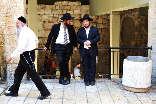 The tzitzit of the tallit katans of two Jewish men are worn outside, while the third man has tucked in his tzitzit.