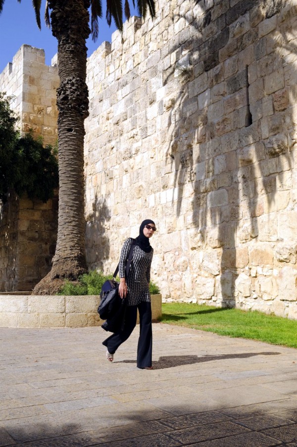 A Palestinian woman walks past the Old City walls of Jerusalem, between the New and Jaffa Gates.