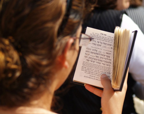 A Jewish woman prays using a siddur (Jewish prayer book) at the Kotel (Western Wall) in Jerusalem.