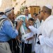 A 13-year-old Jewish boy carries the Torah scroll at the Western (Wailing) Wall as the adults venerate the Torah by kissing the Torah tik (ornate box protecting the Torah scroll).