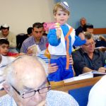 A Jewish boy spins his grogger in the synagogue as he hears Haman's name during the reading of the Megillat.