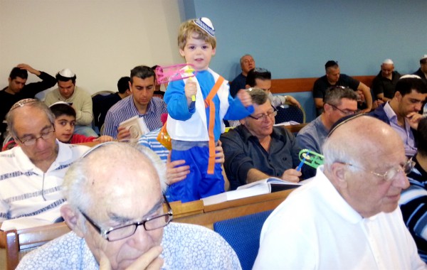 A Jewish boy spins his grogger in the synagogue as he hears Haman's name during the reading of the Megillat.