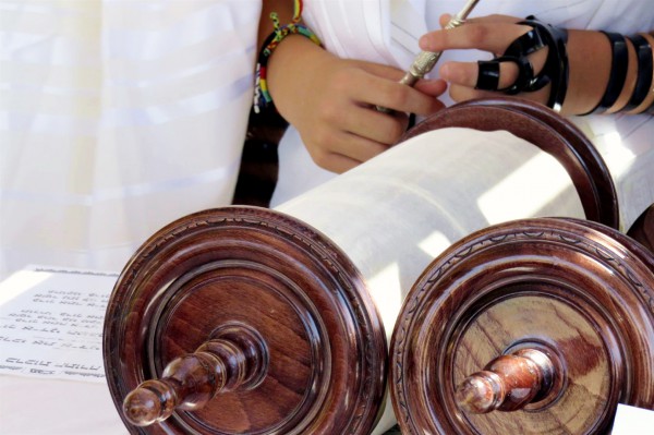 A Jewish youth prepares to read from the Torah scroll.