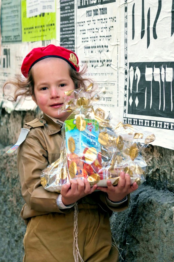 An Orthodox Israeli child dresses like an IDF soldier on Purim. He is carrying a Purim basket.