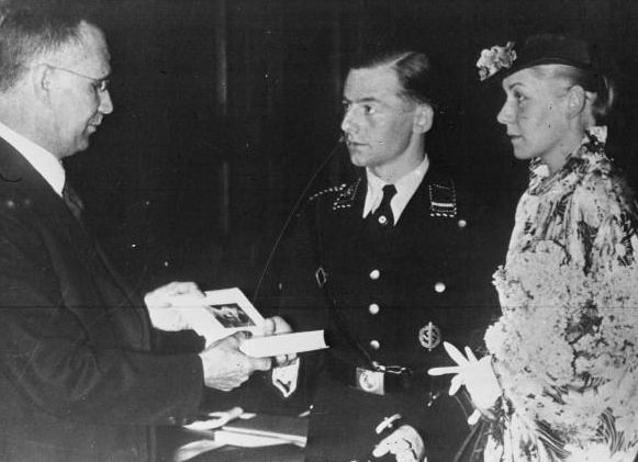 Chancellor Hitler gives a copy of his book Mein Kampf to a newlywed couple during a wedding ceremony in Germany in 1936. Every couple was to receive a copy of it on their wedding day.