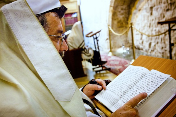 A Jewish man wears a tallit (prayer shawl) and tefillin (phylacteries) as he prays using a siddur (Jewish prayer book) at the Western (Wailing) Wall in Jerusalem.