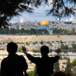 A Christian tourist on the Mount of Olives prays for the peace of Jerusalem.