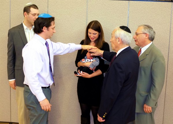 A newborn's great-grandfather, grandfather, and uncle recite the priestly blessing over her. (Photo by Avi and Elina Flax)