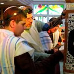 A Jewish 13-year-old male reads from a Torah scroll protected by an elaborately decorated Torah tik.