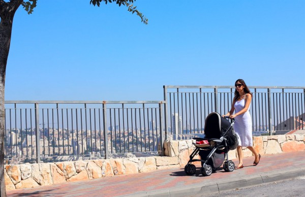 A mother pushes her infant in a stroller on a street in Jerusalem.