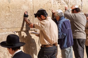 Siddur-Jewish prayer at the Western (Wailing) Wall in Jerusalem. The man wearing tefillin (phylacteries) is reading from a Siddur.