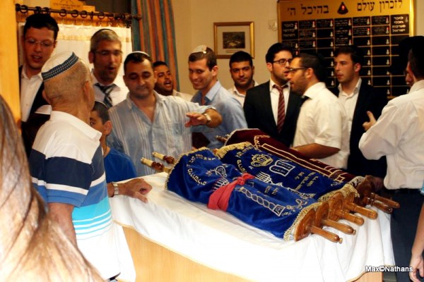 Jewish men circle the Torah scrolls resting on the bimah on Simcha Torah. (Photo by Max@Nathans)