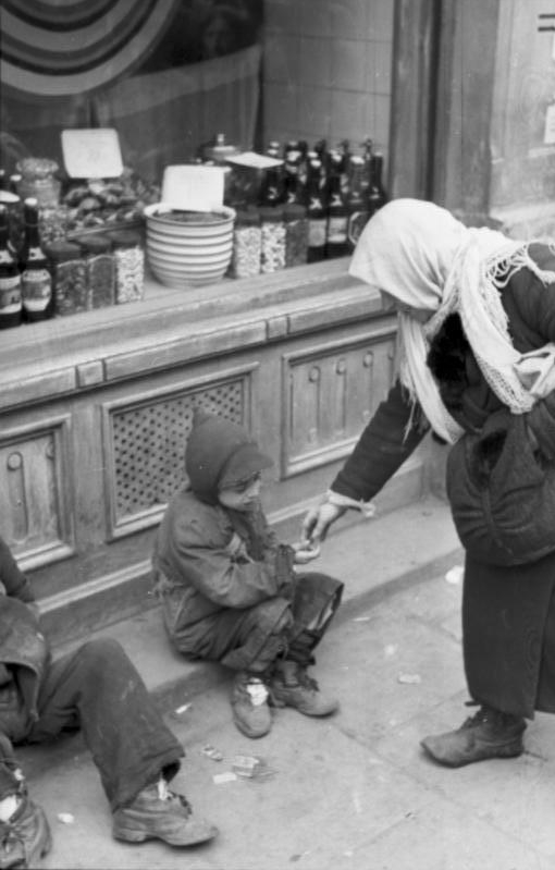 A woman in Poland's Warsaw Ghetto during the Holocaust helps a starving child.