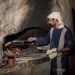 Man bakes bread at a recreated home in Nazareth, wearing period clothes from the time of Yeshua.