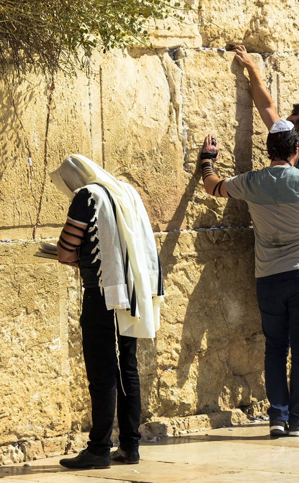 Man wearing a talllit (prayer shawl) is praying at the Western (Wailing) Wall in Jerusalem.