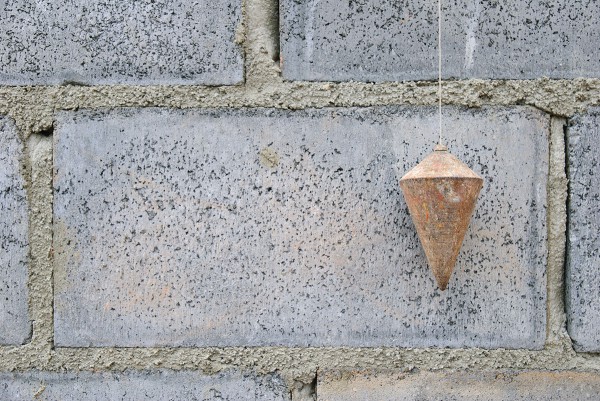 A plumb line is a chord with a weight at the end, a tool used to ensure that a wall is vertically straight and meets architectural standards.
