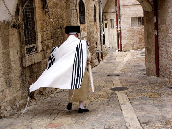 man walks down Jerusalem street wearing a tallit gadol